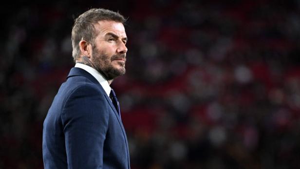 David Beckham im Anzug blickt nachdenklich zur Seite.