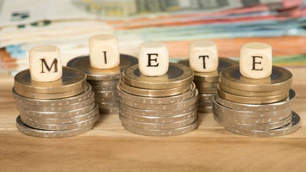 Banknoten, Münzen und Würfel mit der Aufschrift MIETE