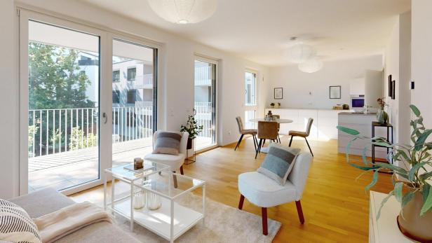 Großzügiger, lichtdurchfluteter Wohn-Essbereich einer Eigentumswohnung von Raiffeisen Wohnbau mit Zugang zu Balkon und moderner Einrichtung.