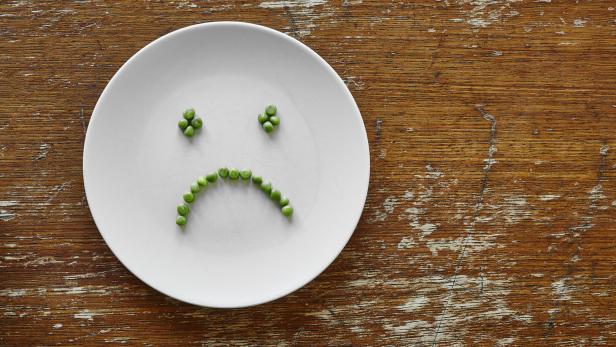 sad hungry smiley face out of peas on plate