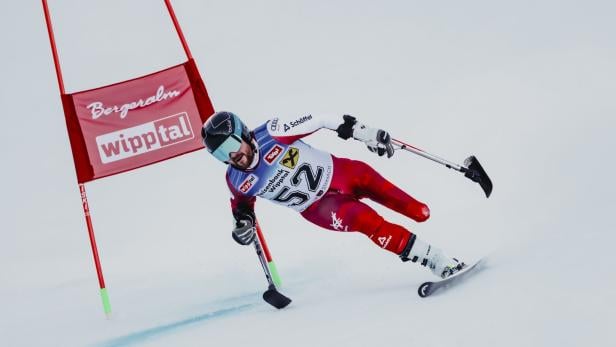 Para-Skiläufer Thomas Grochar mit Startnummer 52 fährt mit hoher Geschwindigkeit um ein rotes Tor auf einer Skipiste.
