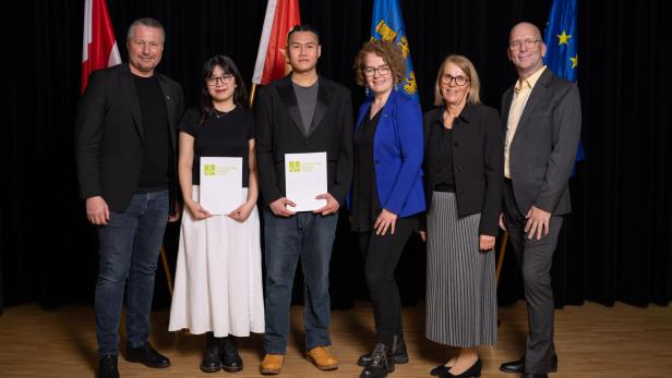 Mehrere Personen stehen vor einer Wand vor der auch die Flaggen von Vietnam, Österreich, Niederösterreich und der EU platziert sind und lächeln in die Kamera.