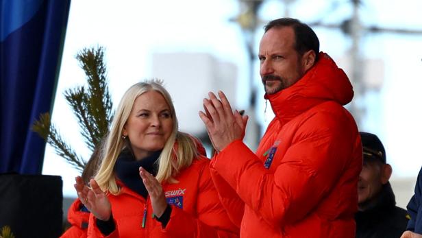 Kronprinz Haakon und Kronprinzessin Mette-Marit klatschen in roten Jacken.