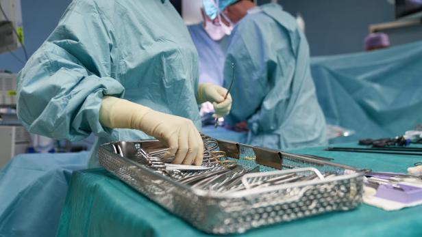 Chirurgisches Team in OP-Kleidung arbeitet mit sterilen Instrumenten an einem Operationstisch.