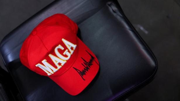 Auf einem schwarzen Stuhl liegt eine rote "MAGA"-Kappe mit einer Unterschrift.
