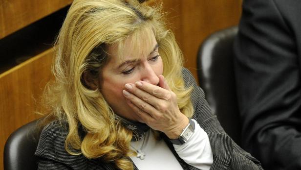 Eine Frau mit blonden Haaren hält ihre Hand vor den Mund.