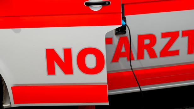 Seitlich geöffnete Tür eines Notarztwagens mit roter Beschriftung und Ladekabel an der Fahrzeugseite.