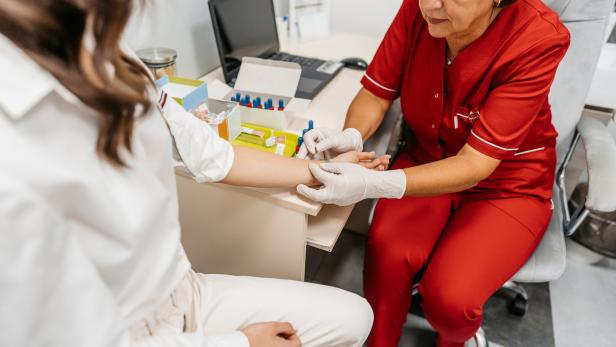 Eine Frau nimmt einer Patientin Blut ab. 