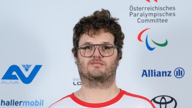Markus Schmidhofer: Ein Mann mit Brille und tätowiertem Arm trägt ein weiß-rotes Sporttrikot mit österreichischem Paralympics-Logo.