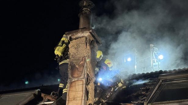 Der gelöschte Dachstuhl, mehrere Feuerwehrleute sind auf dem dampfenden Dach zu sehen.