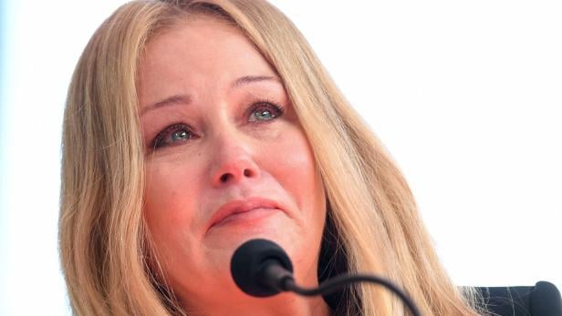 Christina Applegate mit Tränen in den Augen steht vor einem Mikrofon.