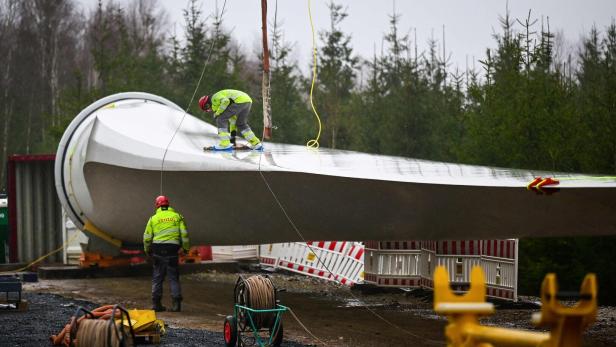 Installation eines Windturbinen-Rotorblatts mit Arbeitern auf Baustelle.