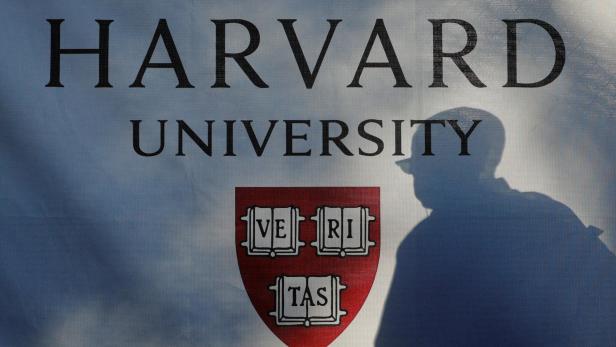 Auf einem Banner ist "Harvard University" mit Wappen und dem Schatten einer Person zu sehen.