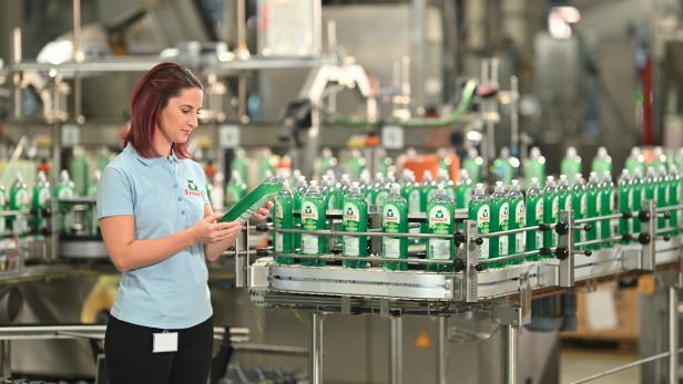 Mitarbeiterin einer Produktionsstätte von Werner & Mertz kontrolliert eine Spülmittel-Flasche.