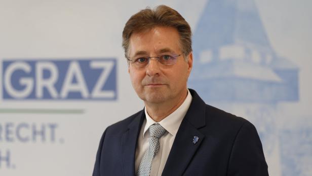 Mann im dunklen Anzug vor Plakat