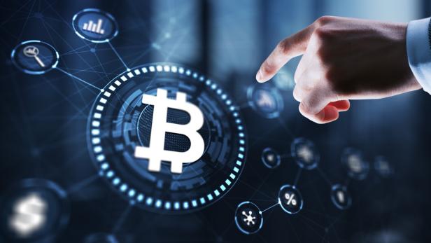 Eine Hand zeigt auf ein digitales Bitcoin-Symbol inmitten vernetzter Finanz- und Technologiesymbole.