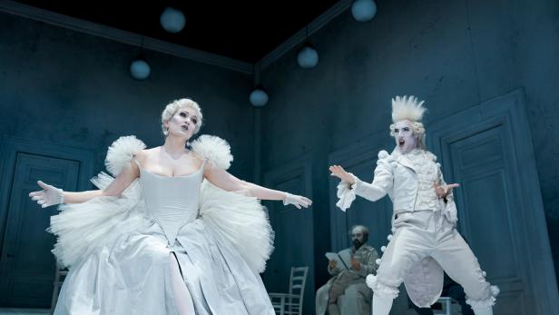Szenenbild aus "L'opera seria" im Theater an der Wien: Zwei Personen in barocken, weißen Kostümen mit weiß geschminkten Gesichtern spielen dramatisch auf einer Theaterbühne.