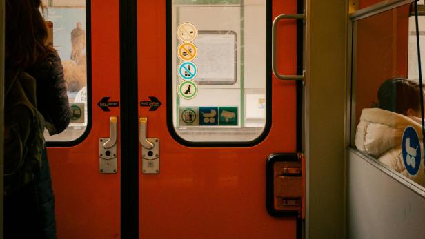 Fahrgast mit Rucksack steht in einer U-Bahn, Verbotsschilder an der Tür sind sichtbar.