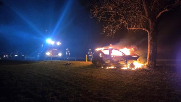 Brennendes Auto bei einem Baum