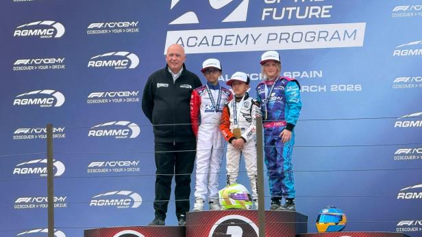 Anna Makolm steht mit zwei weiteren Nachwuchsrennfahrern und einem Offiziellen auf dem Podium der Champions of the Future Academy in Valencia.