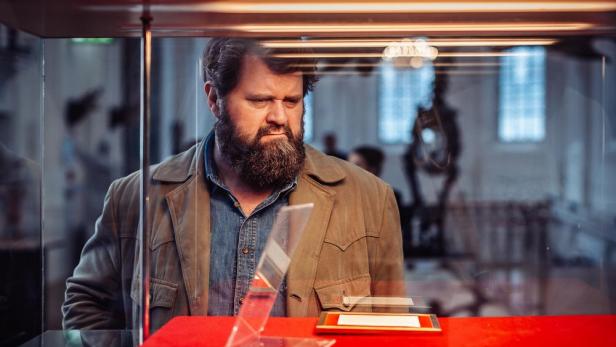 Antoine Monot betrachtet in der Serienrolle eine Vitrine im Museum