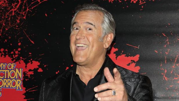 Bruce Campbell in einem gemusterten Sakko zeigt mit dem Finger nach vorne.