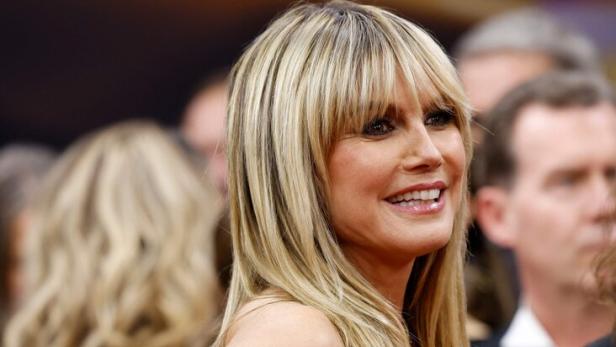 Heidi Klum lächelt in einem blumengemusterten Kleid mit blonden Haaren.