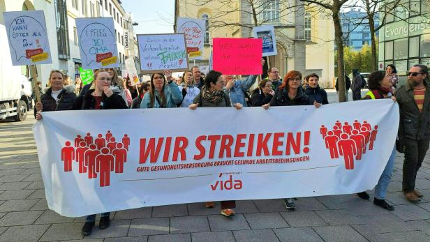 Menschenmenge mit einem Transparent mit der Aufschrift "Wir streiken"