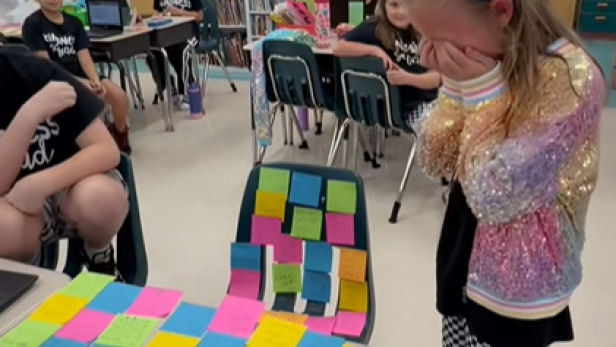 Grundschülerin steht vor Tisch voll bunter Post-its und weint