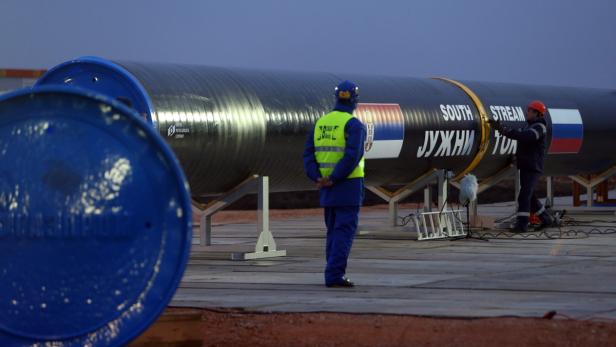 Arbeiter inspizieren eine Pipeline mit der Aufschrift „South Stream“ und Flaggen von Serbien und Russland.