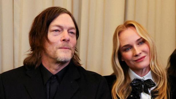 Norman Reedus und Diane Kruger sitzen nebeneinander, beide elegant in Schwarz gekleidet.