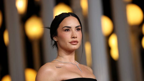 Demi Lovato trägt ein schwarzes, trägerloses Oberteil und eine Halskette.