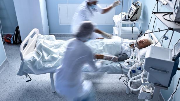 unrecognizable doctors nurses save a patient from death lying on bed in hospital