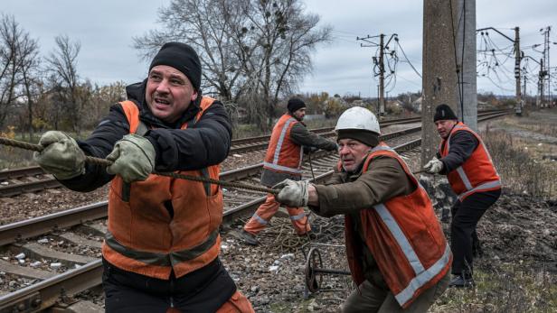 Ukrainische Eisenbahner reparieren gemeinsam eine Stromleitung.
