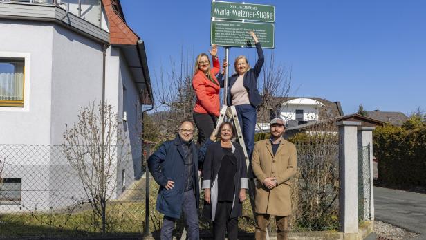 Eine Gruppe von fünf Personen posiert vor dem Straßenschild "Maria-Matzner-Straße" in XIII., Gosting.