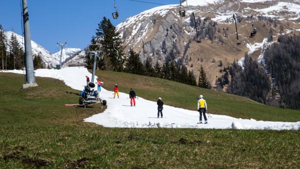 Skifahrer nutzen eine Kunstschneepiste in den Bergen.