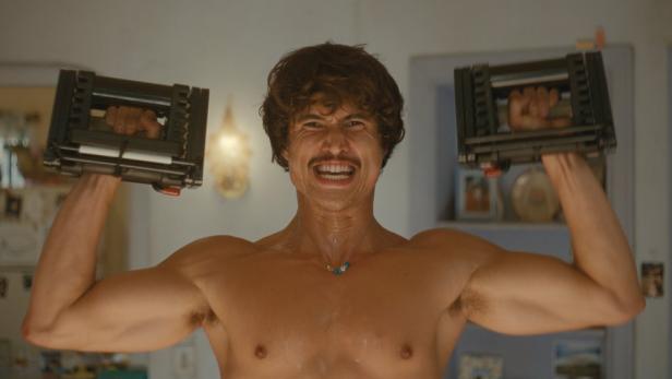 Mann mit muskulösem nackten Oberkörper macht daheim Krafttraining