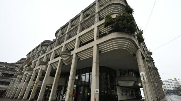 Ein großes, modernes Gebäude mit vielen Balkonen und Säulen steht an einer Straße.