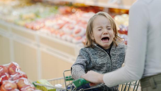 Child crying in shopping cart in supermarket
