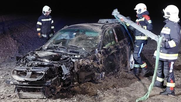 Zerstörtes Auto und Feuerwehrleute