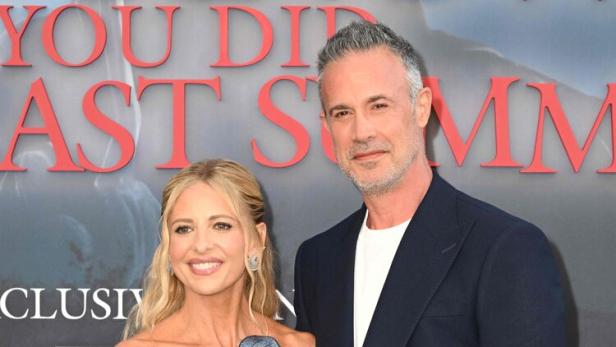 Sarah Michelle Gellar und Freddie Prinze Jr. posieren vor einem roten Schriftzug.