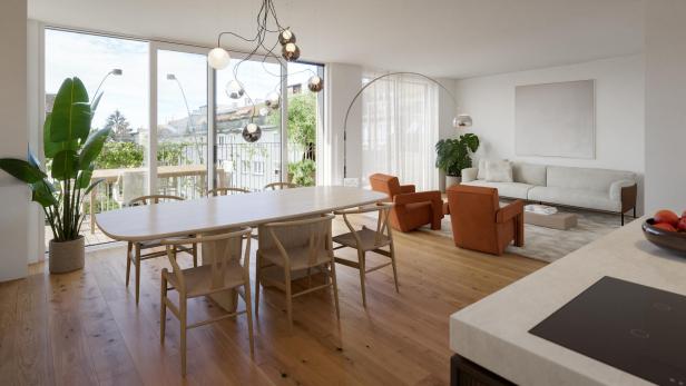 Helles, modern eingerichtetes Wohnzimmer mit großem Esstisch, beigen Sofa, zwei orangefarbenen Sesseln und großen Fenstern.