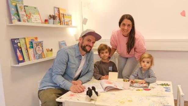 Vater, Mutter und zwei Kinder sitzen an einem Tisch