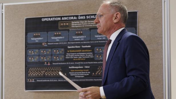 Innenminister Karner im Seitenprofil vor einer Infotafel