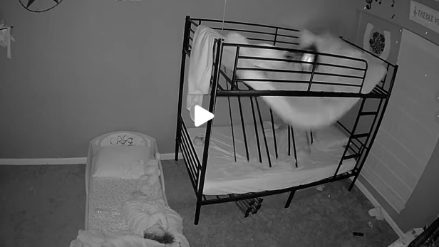 Ein Etagenbett bricht im Kinderzimmer zusammen, Matratze und Kind stürzen auf das untere Bett.