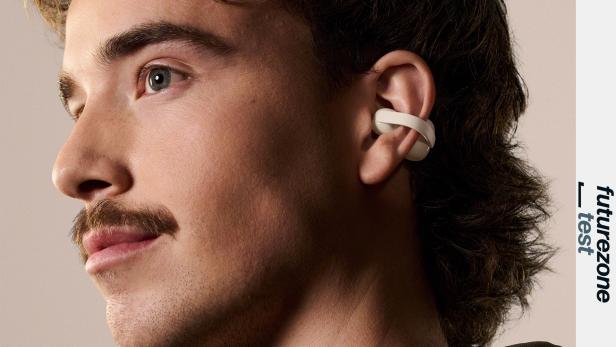 Eine Person trägt einen Sony LinkBuds Clip Kopfhörer in der Farbe Greige am Ohr.