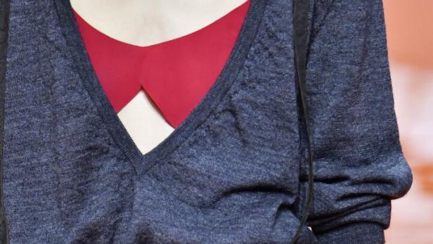 Eine Frau mit einem roten BH, und einer blauen offenen Bluse und einem schwarzen Spitzentuch um die Hüfte