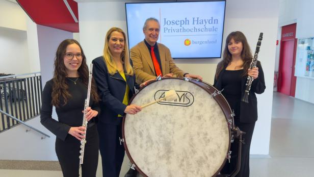 Vier Personen stehen mit einer großen Trommel, einer Querflöte und einer Klarinette in einem modernen Innenraum.