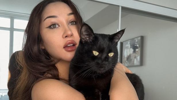 Brünette Frau hält schwarzen Kater auf dem Arm