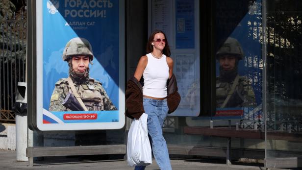 A pedestrian walks past a board glorifying Russian army in Moscow